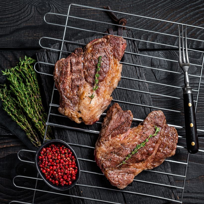 bbq-grilled-chuck-eye-roll-beef-steaks-on-grill-black-wooden-background-top-view.jpg